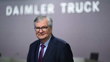 Chef Martin Daum lächelt unter einem Daimler Truck Schriftzug in die Kamera