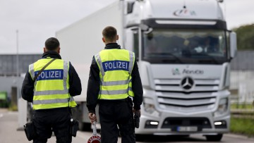 Zwei Polizisten halten einen Lkw zur Kontrolle an