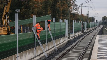 Arbeiter errichten im Bereich des Bahnhofs Dinslaken neben neu verlegten Gleisen eine Schallschutzwand