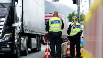 Zwei Polizisten an der Grenzkontrollstelle der Bundespolizei an der A 93 bei Kiefersfelden (Bayern) kontrollieren einen Lkw.