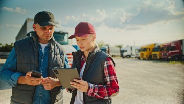 Ein Mann und eine Frau sprechen über den Verkauf eines gebrauchten Lkw (im Hintergrund zusehen)