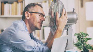 Büroangestellter vor einem Ventilator