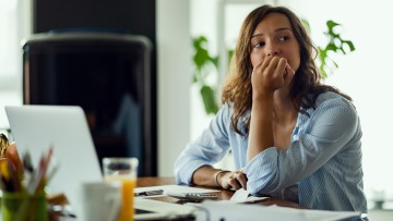 Eine junge Frau sitzt vorm Computer und guckt besorgt