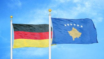 Deutschland-Flagge und Kosovo-Fahne wehen nebeneinander im Wind