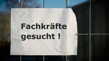 Schild "Fachkräfte gesucht" hängt an einem Gitterzaun