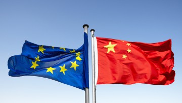 Flaggen von der EU und China flattern in entgegengesetzte Richtungen
