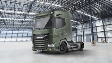 Ansicht des DAF XG+ Emerald Edition von vorn seitlich. Die grün lackierte Sattelzugmaschine parkt in einer Lagerhalle
