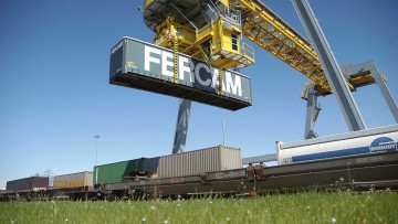 Ein Container von Fercam wird per Kran auf einen Güterzug gehoben