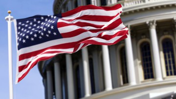 Die Flagge der Vereinigten Staaten von Amerika, die vor dem Kapitol gebäude verschwommen im Hintergrund - Stock-Fotografie