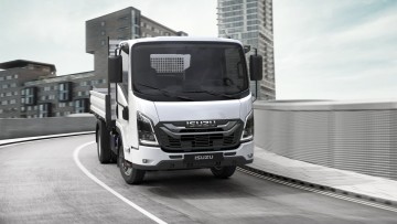 Fahransicht des Isuzu N-Series in urbaner Umgebung. Das weiß lackierte Fahrzeug ist mit einem Kippaufbau ausgerüstet