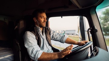 Lkw-Fahrer mit Headset in Fahrerkabine unterwegs