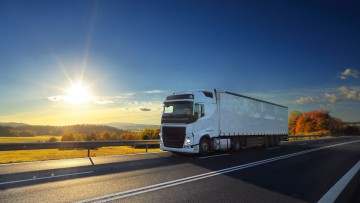 Weisser Lkw fährt in der Sonne auf der Autobahn