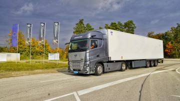 Fahransicht der Superpanther eTopas 600 auf einer Teststrecke. Die in grau lackierte Sattelzugmaschine ist mit einem weißen Kühlauflieger kombiniert