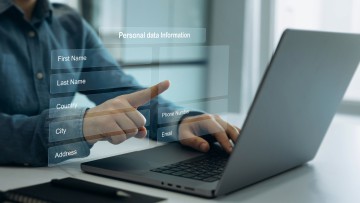 Im Bild ein Mann vor einem Laptop, der persönliche Daten in eine Anmeldemaske eingibt. Das Anmeldeformular ist im Bild als Projektion transparent zwischen Laptop und Mann zu sehen.