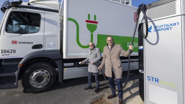 Vor einem E-Lkw von DB Schenker an der Ladestation für E-Lkw des Flughafens Stuttgart stehen, von links: Winfried Hermann Mitglied des Baden-Württembergischen Landtags und Aufsichtsratsvorsitzender des Flughafen Stuttgart, Carsten Poralla, Geschäftsführer