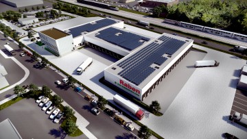 Das Depot der Raben Group in Baden-Baden ist auf einer Fläche von 30.500 m² entstanden. Die Luftaufnahme zeigt Lagerhallen, Laderampen und Lkw. Auf den Dächern ist eine Solaranlage zu erkennen