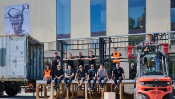 Zusammenarbeit für einen besonderen Transport: Teams von Gebrüder Weiss und den Osterfestspielen Salzburg vor dem Festspielhaus. Im Bild das Team vor einem Lkw mit Requisiten und einem Gabelstapler in Salzburg