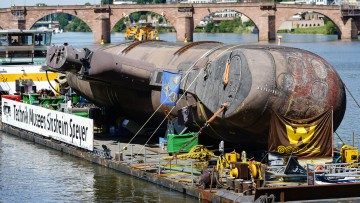 Das U-Boot U17 fährt auf einem Transportschiff vor der Alten Brücke bei Heidelberg in eine Schleuse