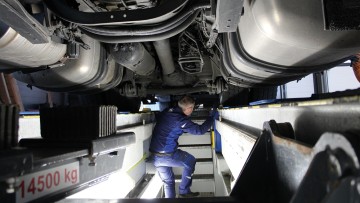 Kfz-Mechaniker prüft Fahrzeug von unten