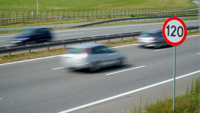 Ein Verkehrsschild mit 120 steht neben einer befahrenen Straße