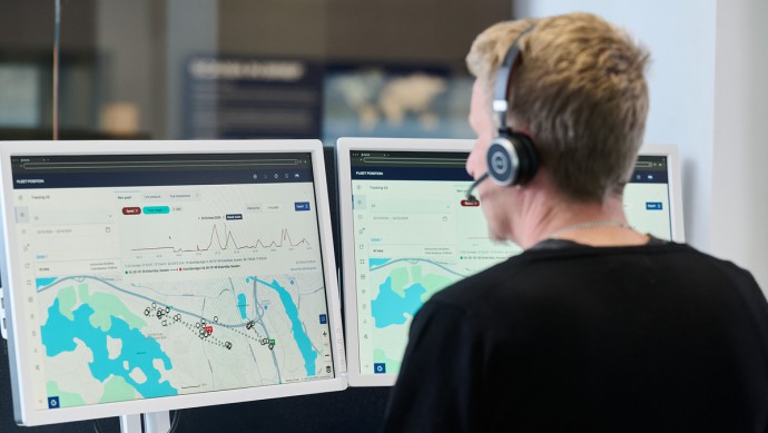 Fuhrparkmanager sitzt am Schreibtisch vor zwei Desktops mit Scania Mixed Fleet Connectivity