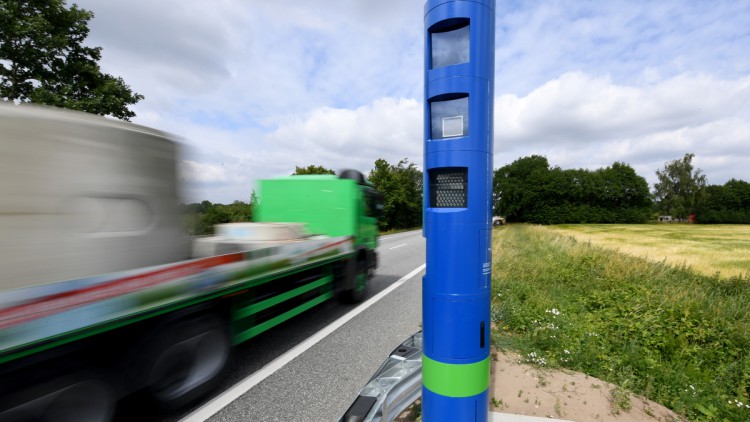 Eine Kontrollstelle zur Erfassung der Maut für LKW steht an einer Bundesstraße und ein Lkw fährt an ihr vorbei