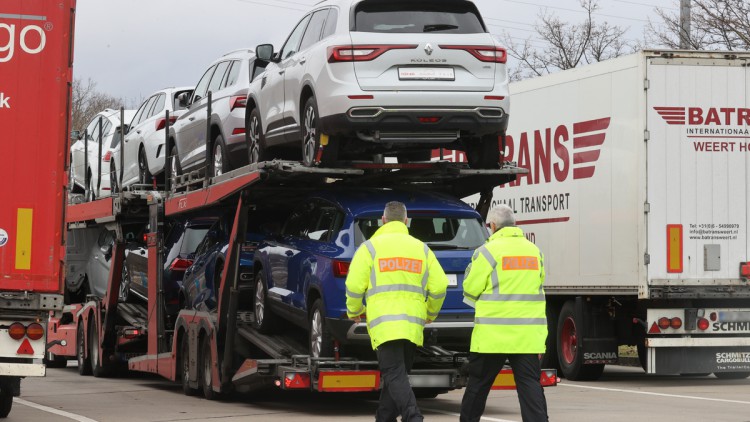 Polizeibeamte kontrollieren einen Lkw, der mit Autos beladen ist