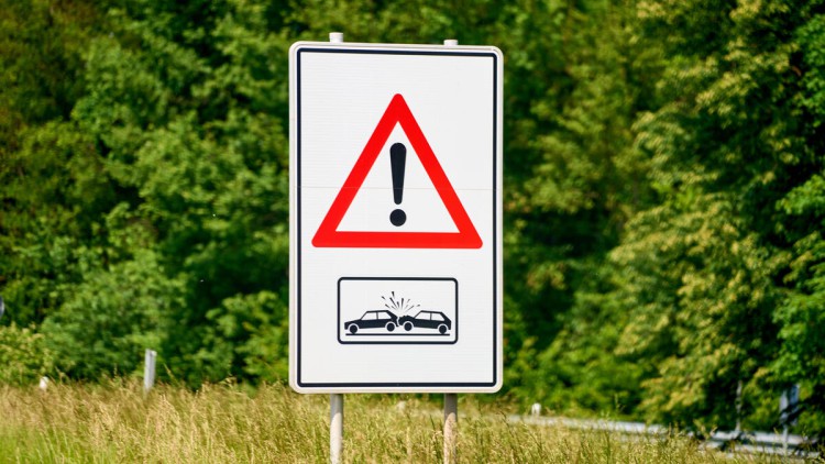 Verkehrssschild, Warnung Auffahrgefahr und Unfallgefahr im Straßenverkehr in der grünen Natur