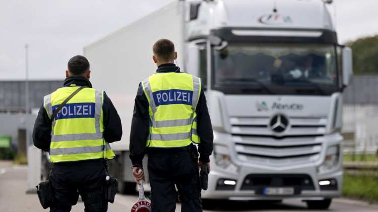 Zwei Polizisten halten einen Lkw zur Kontrolle an