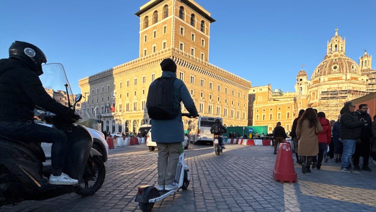 Ein Mann ohne Helm (M) fährt mit einem Elektro-Tretroller auf der Straße in der Innenstadt