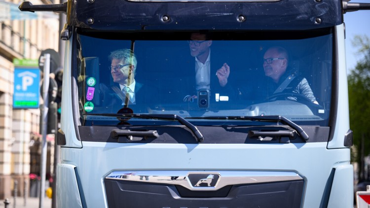 Bundesverkehrsminister Patrick Schnieder (l, CDU), macht am 23. April 2026 zusammen mit Wolfgang Brand, CFO von Milence, dem Betreiber des größten öffentlichen Schnellladenetzes für schwere Nutzfahrzeuge in Europa, und dem Fahrer Michael Noll (r) von MAN 