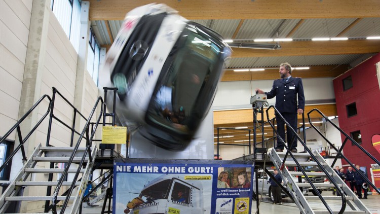 Mann steht neben einem Lkw-Simulator, der sich wild dreht und einen Unfall simuliert