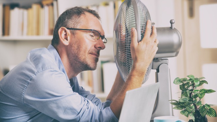 Büroangestellter vor einem Ventilator