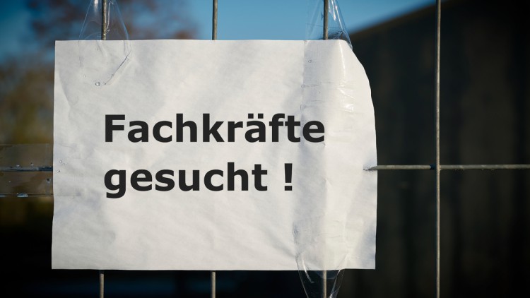 Schild "Fachkräfte gesucht" hängt an einem Gitterzaun
