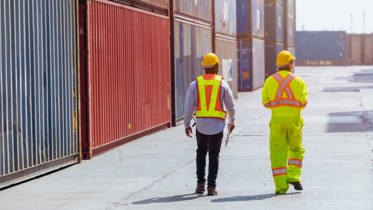 Hafenmitarbeiter zwischen den Containern an Land