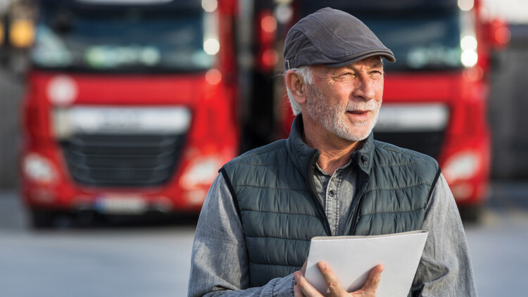 Altersvorsorge Unternehmen/ älterer Herr vor roten Lkw