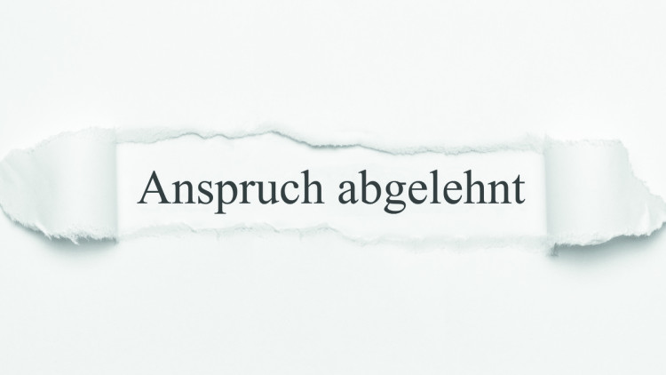 Anspruch abgelehnt schriftlich hinter aufgerissenem Papier