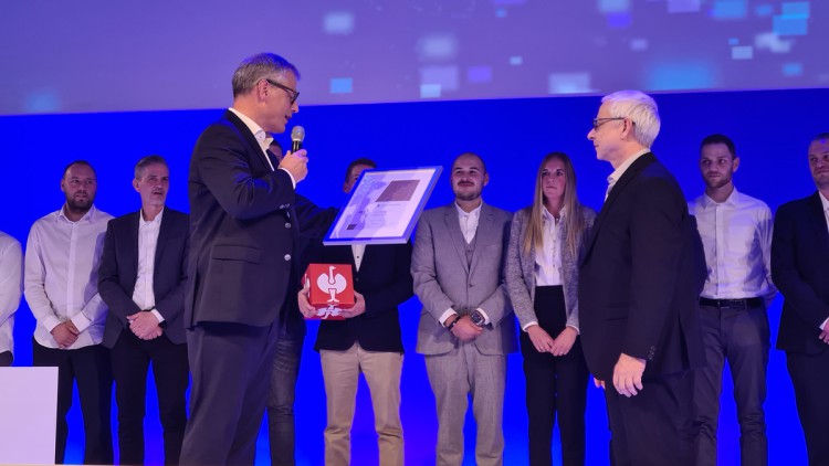 Strauss hat den Deutschen Logistikpreis 2025 gewonnen. Zu sehen ist die Preisübergabe in Berlin, bei der die Urkunde an den Preisträger übergeben wird, im Hintergrund stehen weitere Personen