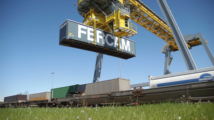 Ein Container von Fercam wird per Kran auf einen Güterzug gehoben