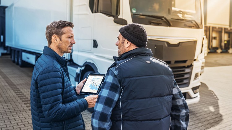 DKV Mobility erweitert digitales Portfolio um eigenes TMS Männer vor Lkw mit DKV TMS auf dem Tablet