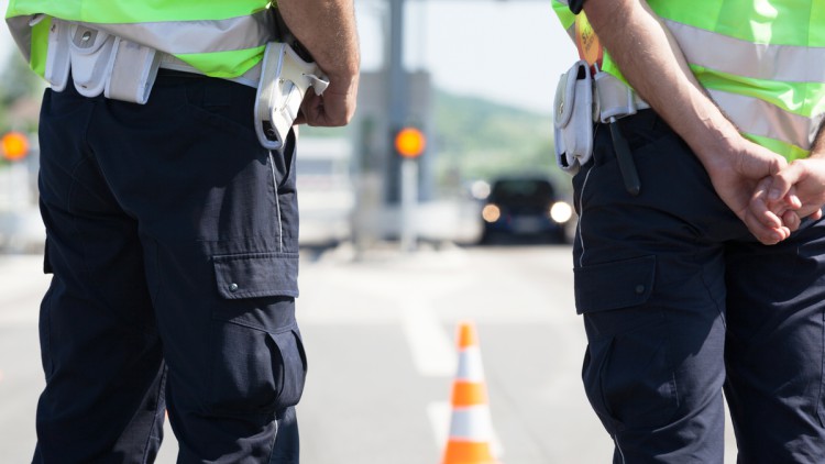 Die Beine von zwei Polizisten bei einer Verkehrskontrolle auf der Autobahn