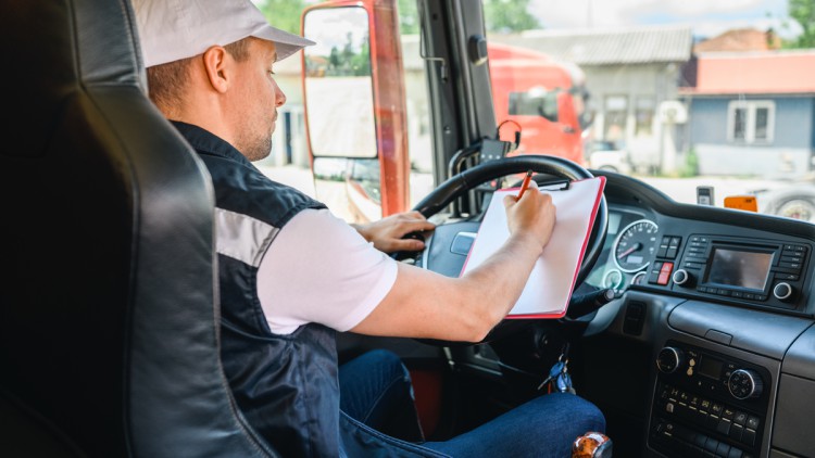 Lkw Fahrer füllt am Lenkrad Fahrtenschreiberdaten aus