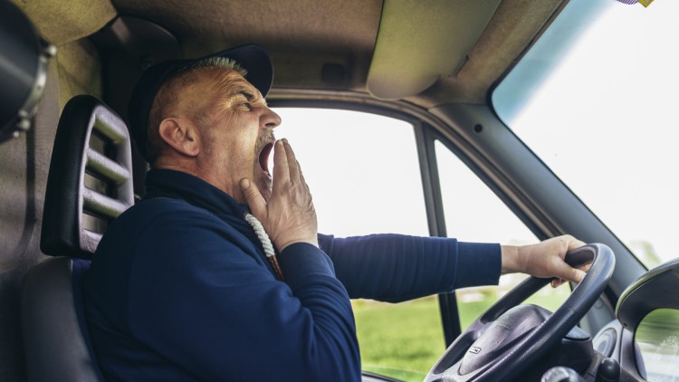 Müder Lkw-Fahrer gähnt am Steuer