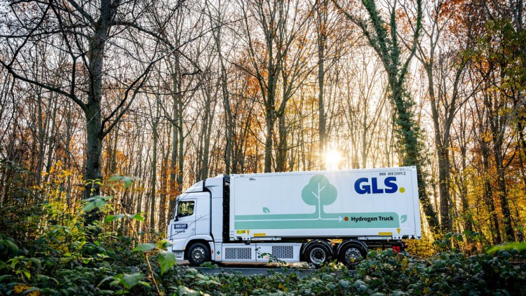 Der GLS Wasserstoff-Lkw fährt bei Sonnenschein im Herbst durch einen lichten Wald