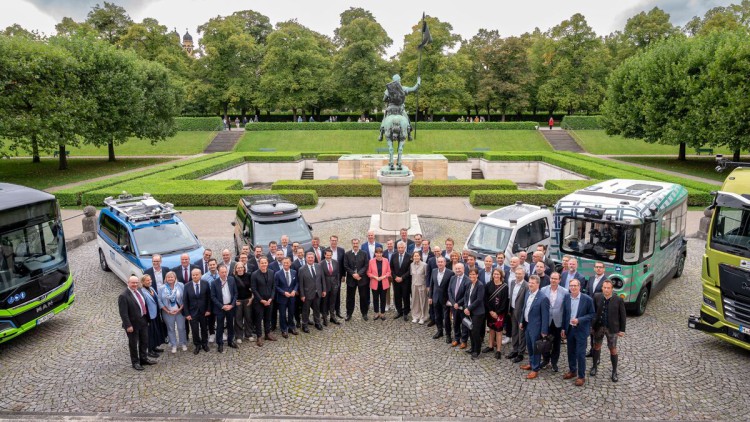 Rund 50 Partner gründen bei der IAA Mobility eine Initiative für autonomes Fahren. Mitinitiator ist die TU München.Auf dem Bild sind diese vor verschiedenen Nutzfahrzeugen (Bus, Shuttle, Lkw) zu sehen. Die Fahrzeuge stehen im halbkreis hinter ihnen