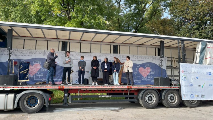 Fünf Azubis mit Gerhard Grünig und Sabine Lehmann auf der Lkw-Bühne