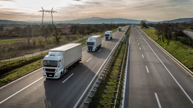 Weisse Lkw fahren hintereinander auf der einer leeren Autobahn