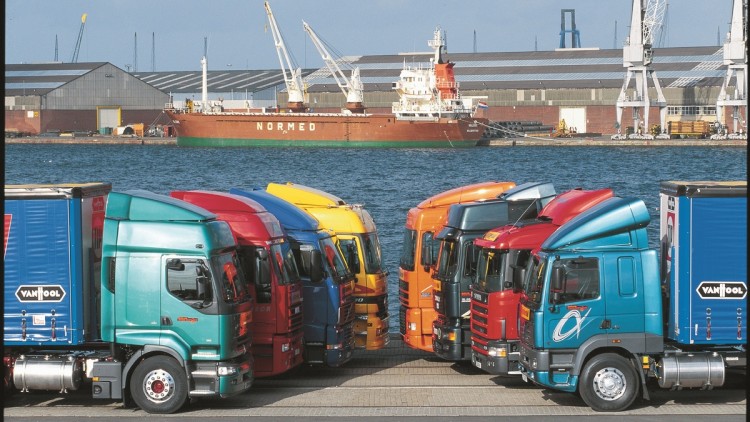 Acht Sattelzugmaschinen parken im Jahr 2000 in Reih und Glied in einem Hafengebiet