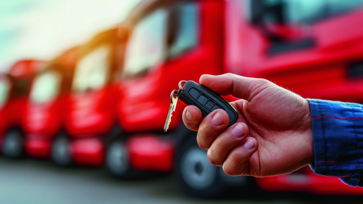 Autoschlüssel in der Hand, im Hintergrund stehen Lkw