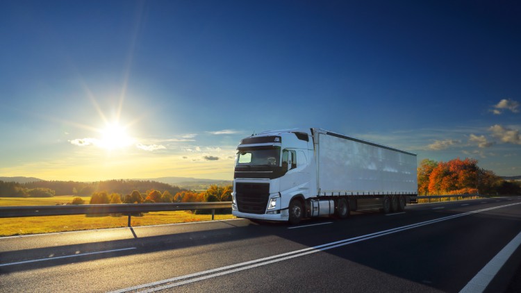 Weisser Lkw fährt in der Sonne auf der Autobahn